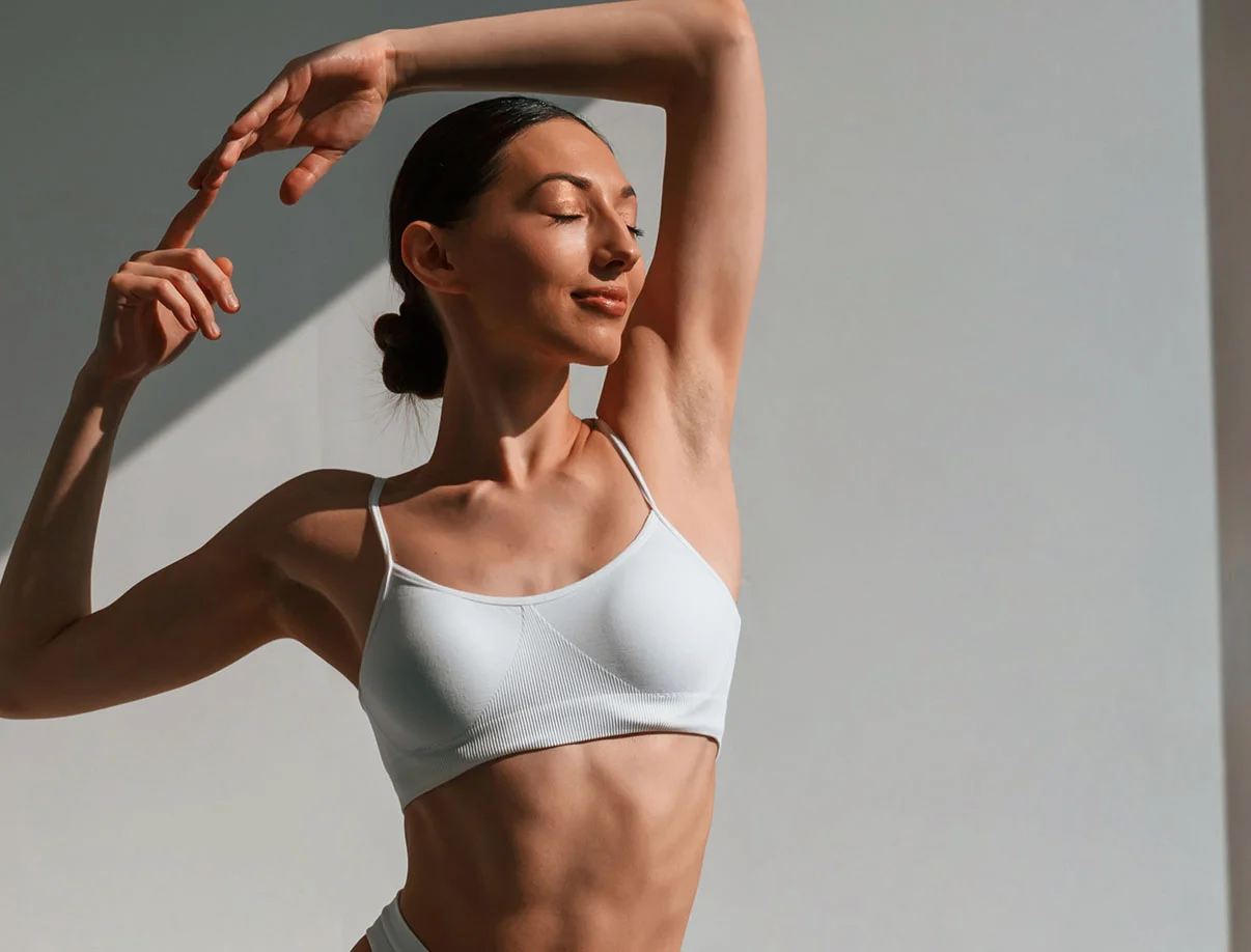 Woman in white sportswear posing gracefully in soft natural light - Breast Augmentation in West Hollywood, CA